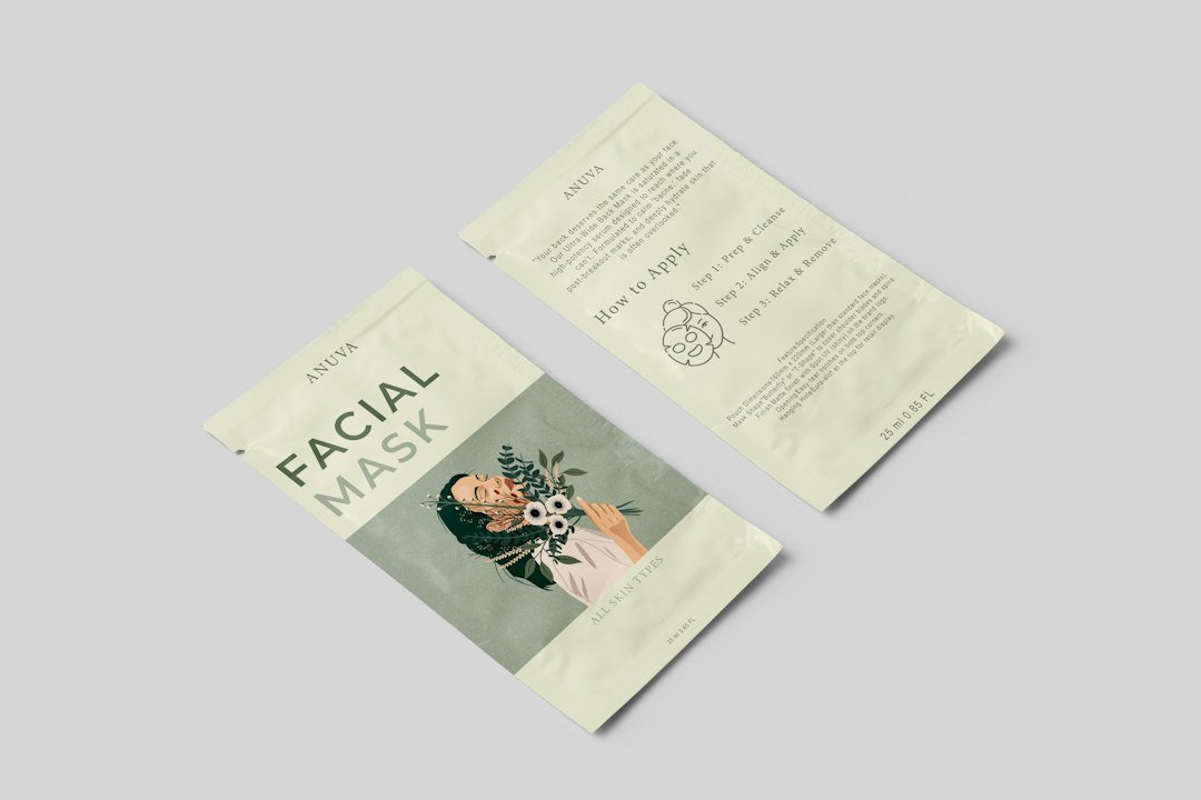 Two facial mask packets with illustrated botanical designs on a plain grey background